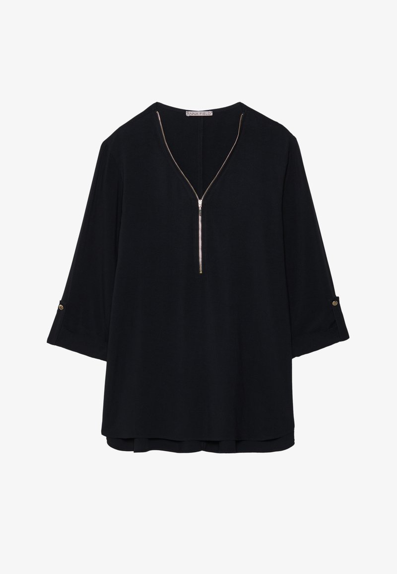 Top negro con escote en V y cierre de media cremallera; cuenta con mangas tres cuartos con puños enrollados y acentos de herrajes en tono dorado.