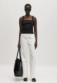 Schwarzes geripptes Tanktop, weiße Jogginghose mit Kordelzug, schwarze Tasche, übergroße schwarze Sonnenbrille, glattes Material, lockere Passform, minimalistisches Design.