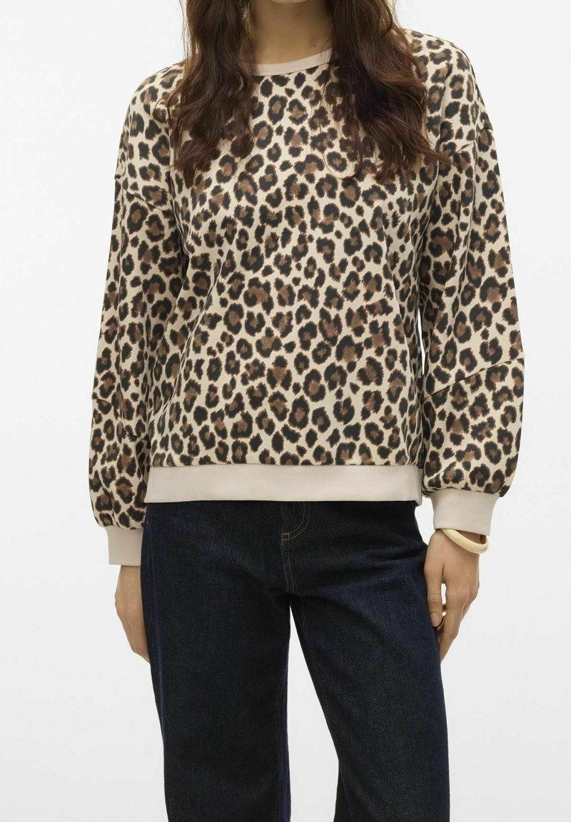 Sudadera de estampado de leopardo en tonos beige y marrón, de tejido suave, con mangas largas, puños elásticos y dobladillo acanalado, combinada con jeans de mezclilla oscuros.