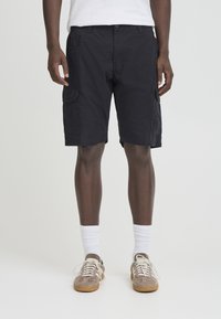 Marine cargoshorts van lichte stof, met meerdere zijzakken en een relaxed fit, gecombineerd met beige sneakers en witte sokken.