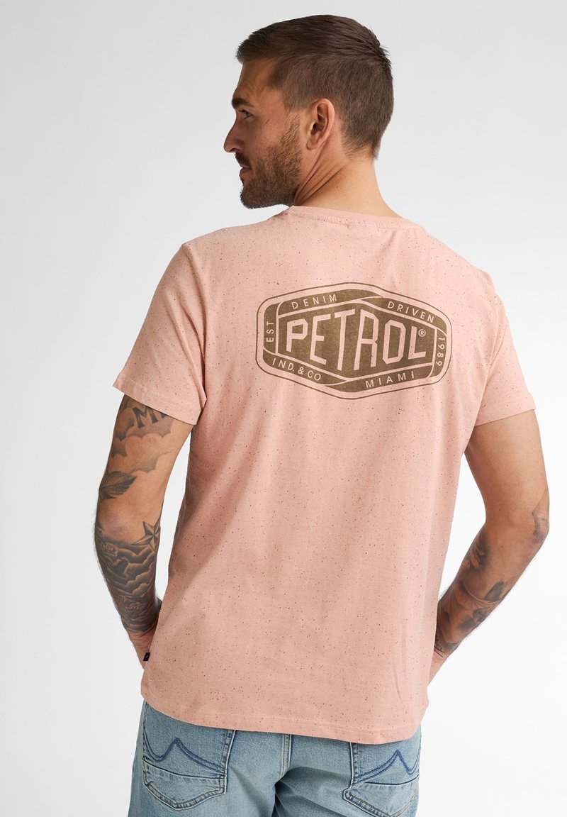 Světle růžové bavlněné tričko s tečkovanou texturou. Na zadní straně se nachází velké hnědé logo "PETROL". Krátké rukávy, kulatý výstřih.