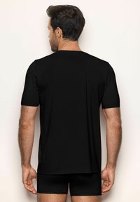 T-shirt noir à manches courtes, fabriqué en coton doux, avec un col rond et un ourlet droit. Porté avec un short noir assorti.