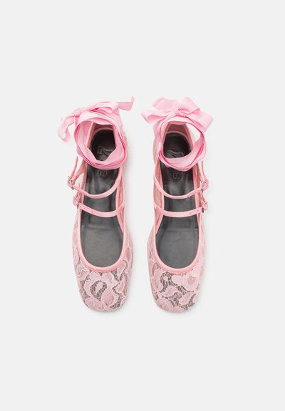 Bailarinas de encaje rosa con cintas en el tobillo, que presentan una parte superior de tejido suave, punta redonda y un patrón de encaje texturizado sobre una plantilla gris.