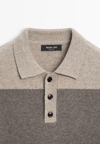 Béžové a šedé pletené polo tričko s žebrovaným límcem, třemi tmavými knoflíky a hladkou texturou s vodorovnými barevnými bloky.