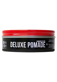 Metallburk med svart kropp och röd lock. Etiketten har texten "DELUXE POMADE" i fetvita bokstäver. Slät yta, cylindrisk form.