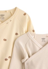 Dwa niemowlęce ubranka z długim rękawem wykonane z miękkiej prążkowanej tkaniny; jedno w jasnopółżółtym kolorze z brązowymi plamkami, drugie jednolite w kolorze ecru, wyposażone w zatrzaski.