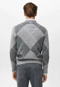 Suéter gris de argyle con un patrón de diamantes, acentos en gris claro, dobladillo y puños acanalados, y una textura suave. Lleva puesto sobre jeans gris oscuro.