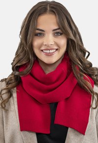 Red knitted scarf with ribbed edges, displayed around the neck. Soft texture, vibrant color, and a cozy design suitable for cold weather.