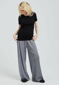 Black ribbed t-shirt paired with light gray wide-leg pants. The outfit features a relaxed fit and a smooth texture, with subtle fabric movement.