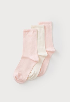 Tres pares de calcetines en rosa claro, crema y rosa más oscuro, con una textura suave y un sutil logotipo en los puños.
