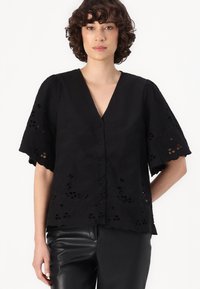 Black short-sleeve blouse with a V-neck, featuring floral embroidery, cut-out details, and a button front. Smooth, lightweight fabric.
