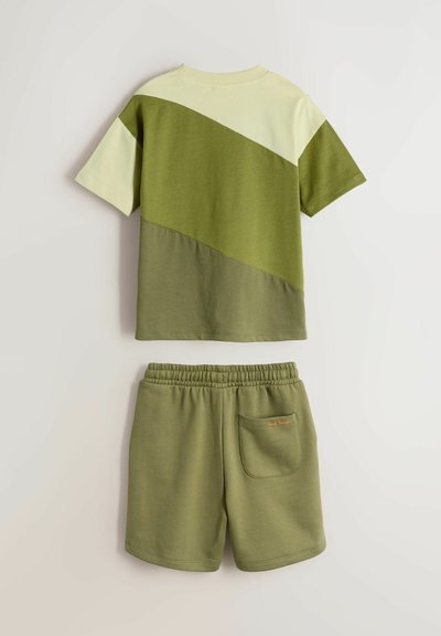 Kortærmet T-shirt med tre diagonale grønne nuancer og matchende grønne shorts med elastik i livet og en baglomme.