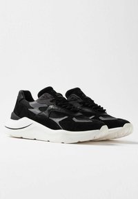 Sorte sneakers med en blanding af ruskind og mesh-materialer, strømlinet design og en hvid sål. Indeholder diskrete logodetaljer på siden.