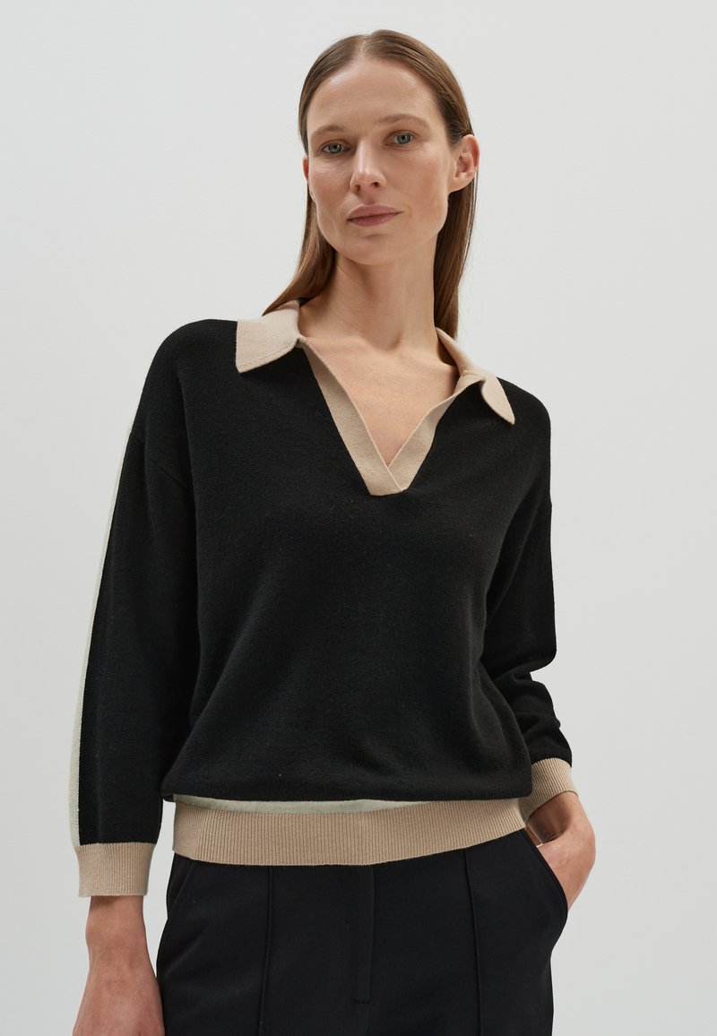 Maglione nero con colletto e orlo color crema. Design a V, maniche lunghe e texture morbida. Dettagli al colletto e ai polsini.