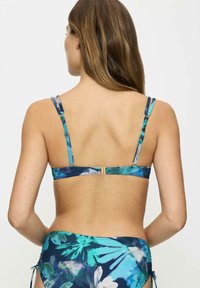 Kwiatowy bikini top z regulowanymi, wielokolorowymi ramiączkami. Materiał jest gładki, z odważnym niebiesko-zielonym tropikalnym wzorem. Złoty detal z zapięciem.