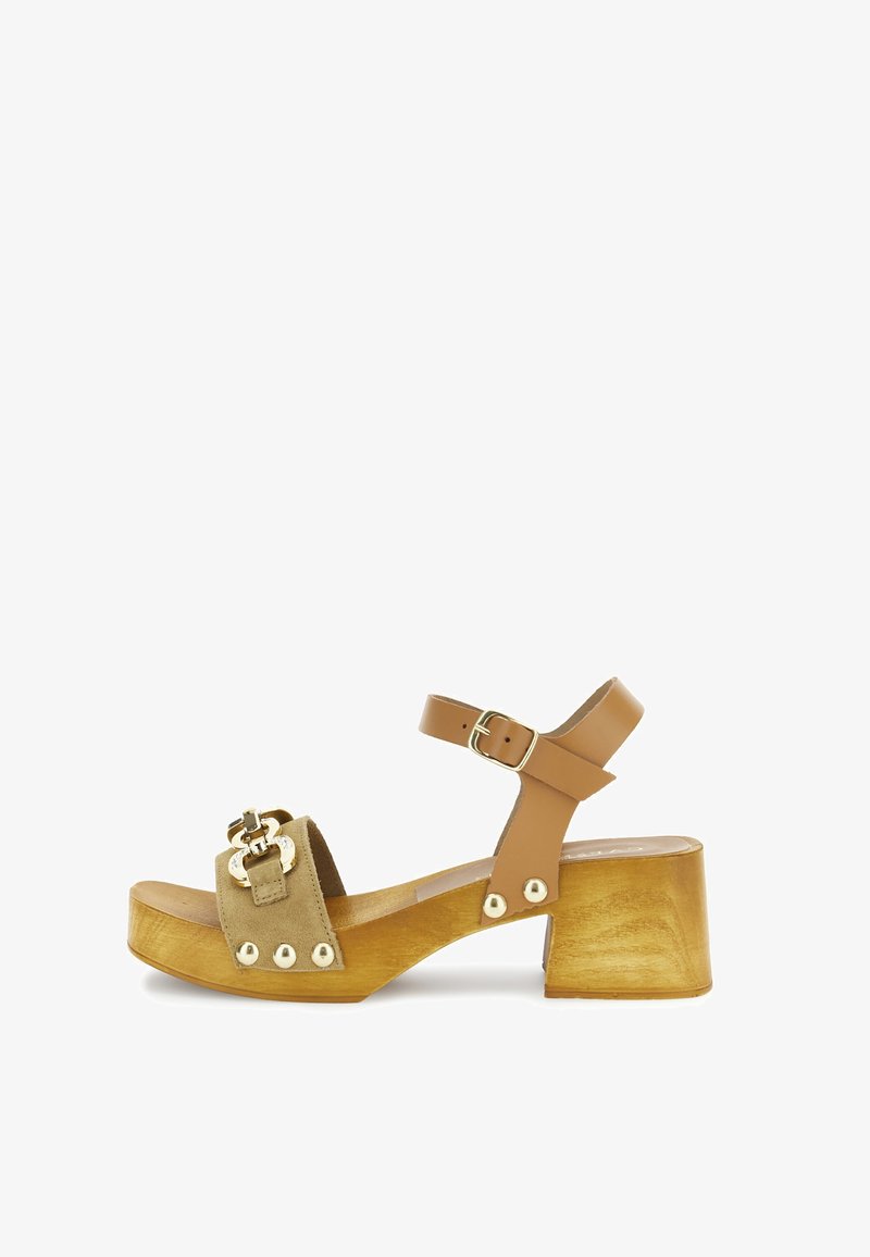 Bruine leren sandaal met enkelbandje, voorzien van een gewatteerde beige suede voetbed en goudkleurige hardware, met een chunky houten hak en decoratieve studs.