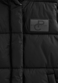 Czarna puchowa kurtka o gładkiej, błyszczącej fakturze, z wyraźną prostokątną naszywką z czarnym haftem z napisem "POLO CLUB".