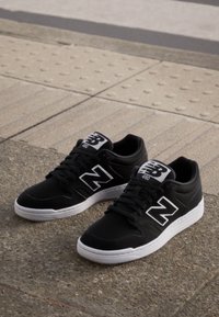 Adidași negri cu accente albe, având un superior texturat, șireti plata și o talpă din cauciuc. Logo-ul notabil pe limbă și pe lateral.