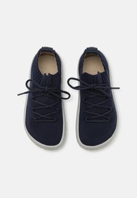 Chaussures en tricot bleu marine avec une tige texturée, un design ajusté et une semelle en caoutchouc grise. Elles disposent de lacets pour un ajustement.