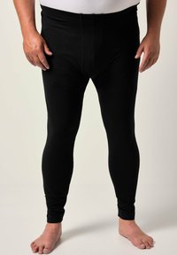 Leggings neri con una texture liscia, caratterizzati da un design aderente e una vita elastica. Il tessuto appare elastico e opaco.