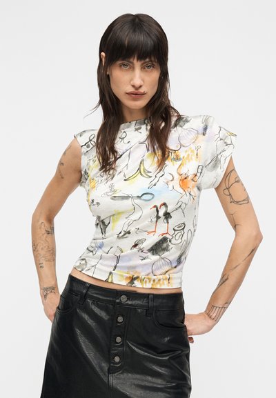Εφαρμοστή λευκή κοντή μπλούζα με πολύχρωμο αφηρημένο σχέδιο. Μανίκια τύπου καπέλο και απαλό ύφασμα. Συνδυάζεται με μαύρη δερμάτινη φούστα με κουμπιά.