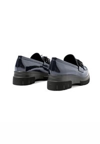 Mocassini in pelle verniciata blu navy con suola in gomma nera spessa e dettagli a frange sulla tomaia. Texture liscia con una finitura elegante.
