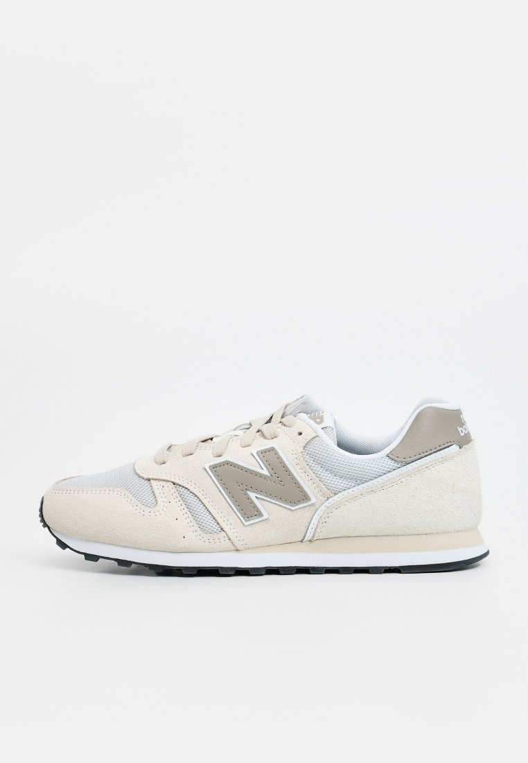 Baskets beige et grises avec une tige en daim et en mesh, présentant un logo "N" bien en vue, un système de laçage et une semelle en caoutchouc.