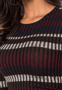 Haut en maille côtelée multicolore avec des rayures horizontales en bordeaux, marine et blanc. Encolure ronde avec une finition texturée.