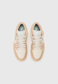 Baskets beige et crème avec une tige en cuir lisse, une toe perforée, des accents bleu clair et des lacets plats. Logos Jumpman subtils visibles.