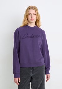 Purple sweatshirt with a ribbed crew neck and raglan sleeves. Features embroidered "Carhartt" text on the front. Soft fabric texture.