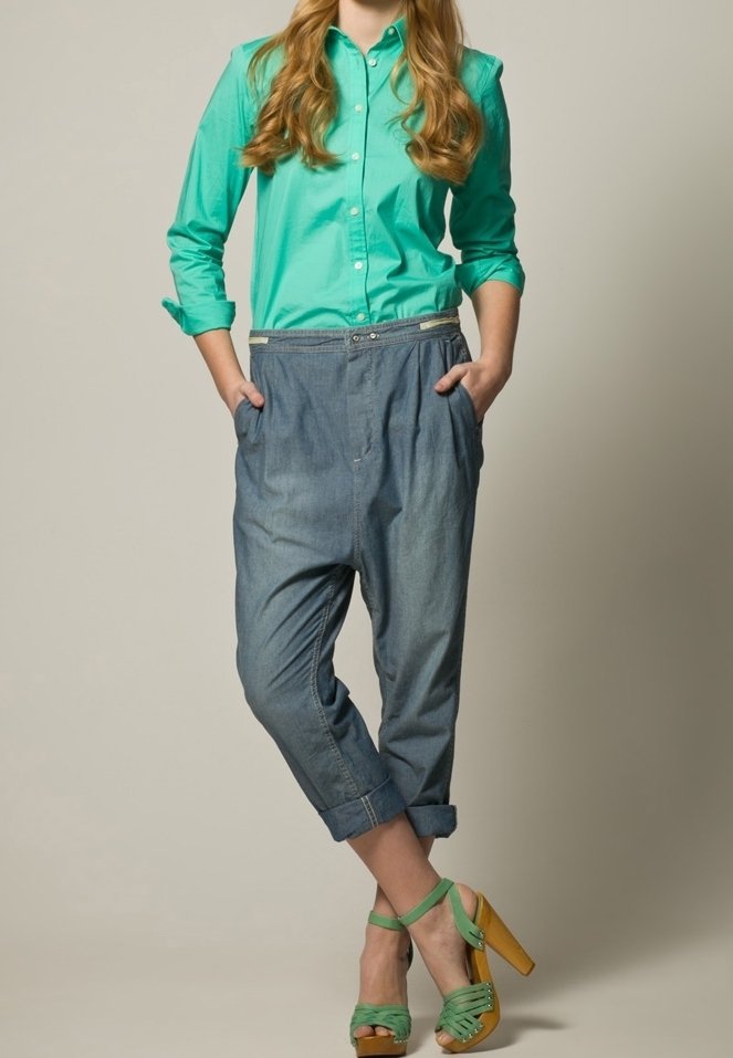 Camicia verde con bottoni, pantaloni denim cropped con risvolti e sandali verdi con tacco in legno a strappi.