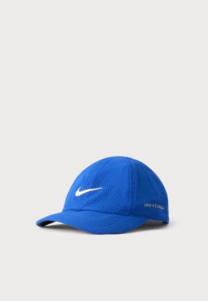 Niebieska czapka bejsbolowa Nike z białym logo typu swoosh i małymi otworami wentylacyjnymi z przodu i po bokach na jasnoszarym tle.