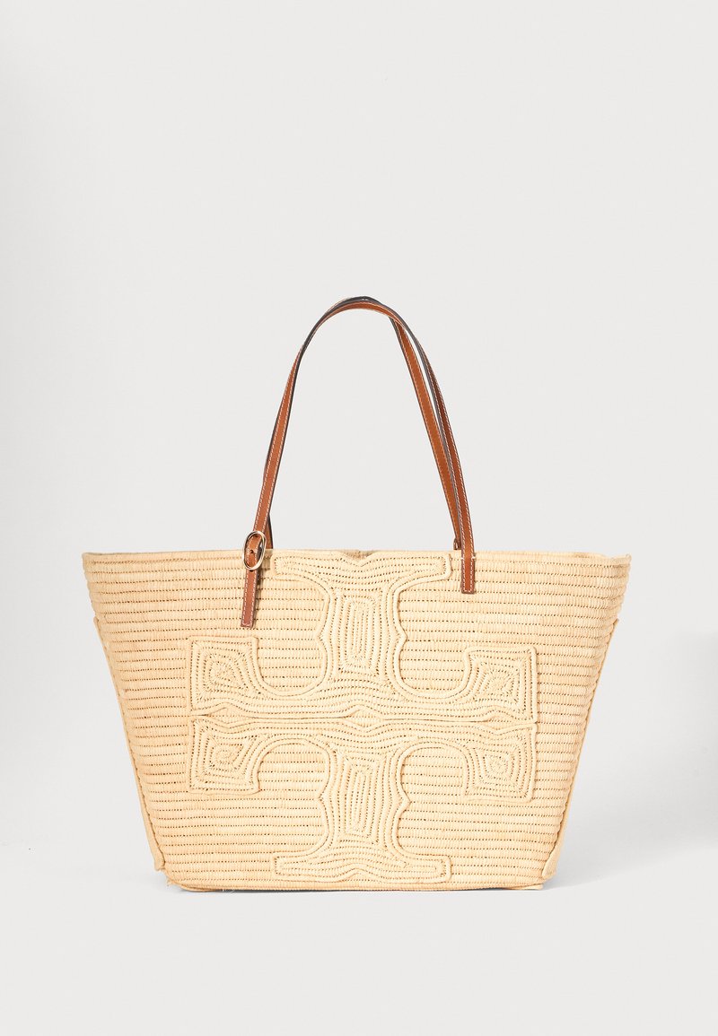 Sac fourre-tout tissé beige avec un grand motif croisé texturé à l'avant et des bretelles en cuir marron.