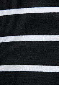 Svart stickad tyg med horisontella vita ränder; texturerad yta med ribbat mönster. Ränderna varierar i bredd och skapar kontrast.