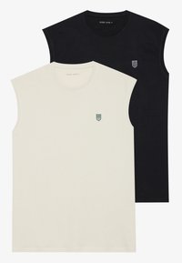 Two sleeveless T-shirts: one cream with a small green logo, the other black with a white logo. Soft cotton fabric, casual design.