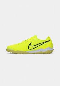 Scarpe da atletica giallo neon con tomaia testurizzata, logo Nike nero e suola in gomma, caratterizzate da un design a profilo basso e chiusura con lacci.