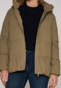 Olivově zelená péřová bunda s kapucí, lehký materiál, přední zip a boční kapsy, kombinována s tmavým svetrem a džíny.