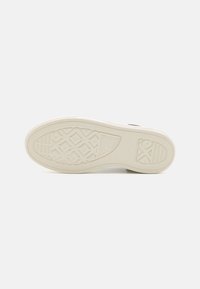 Rubber sneaker outsole in cream with textured pattern, featuring a diamond grip design and smooth edges.