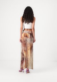 Maxi skirt in a multi-toned abstract print featuring warm earth tones. Made of lightweight fabric with a flowy design and slit accents.