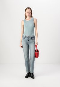 Hele sinine ribadega tank top koos heledate teksadega. Mustad pahkluu saapad ja väike punane õlakott täiendavad riietust.