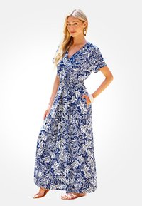 Vestido maxi con escote en V profundo, mangas cortas, en azul marino y con estampado floral blanco; cuenta con cintura elástica y bolsillos laterales.