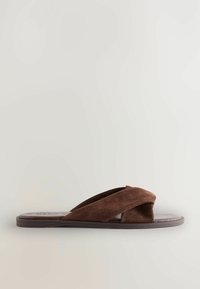 Lame pruun sandaal laia suede ristiriides rihmadega ja madala tallaga heledal taustal.