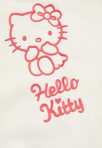Tejido blanco con un gráfico de Hello Kitty en color rosa encima del texto "Hello Kitty" en una fuente rosa similar. El diseño incluye un lazo y detalles del personaje.