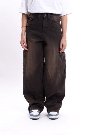 Cargo pants in dark brown denim with a loose fit, high waist, multiple side pockets, and stitched detailing, paired with blue and white sneakers.