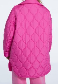 Rosa steppjacke mit Wellenmuster, oversized Design und Kragen. Die Säume sind leicht geschwungen und weisen sichtbare Nähte auf.