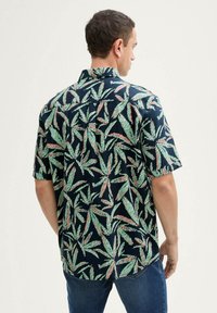 Camisa de botones de manga corta con fondo azul marino y patrones de hojas verdes y rosas, hecha de una tela ligera con un corte relajado.