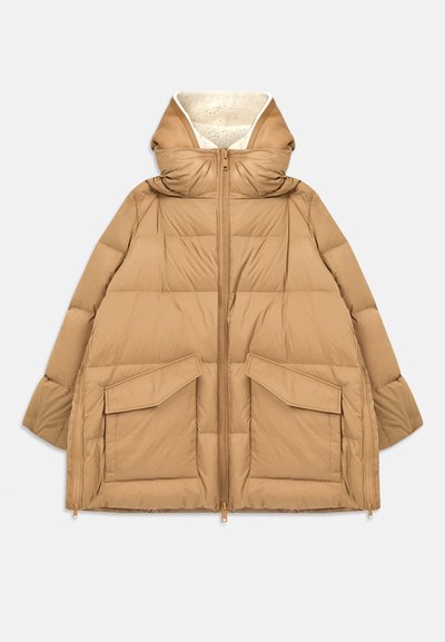 Beige vuorattu takki, jossa on suuret etutaskut, täysimittainen vetoketju, leveä huppu shearling-vuorauksella ja sivuvetoketjut helmassa.