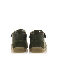 Botas infantiles de cuero y ante verde con una lengüeta en el talón, correa de velcro y suela de goma. Superficies lisas y texturizadas. Nombre de la marca en el talón.