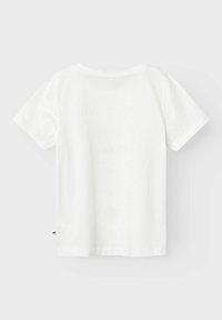 Camiseta de algodón blanca con mangas cortas, un escote redondeado y un pequeño detalle de logo en el dobladillo inferior izquierdo. Textura de tela suave.