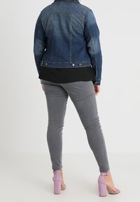 Tummanpesun farkkutakki, yhdistettynä mustaan yläosaan ja harmaisiin skinny-farkkuihin. Vaaleanpunaiset korkokengät viimeistelevät asun.